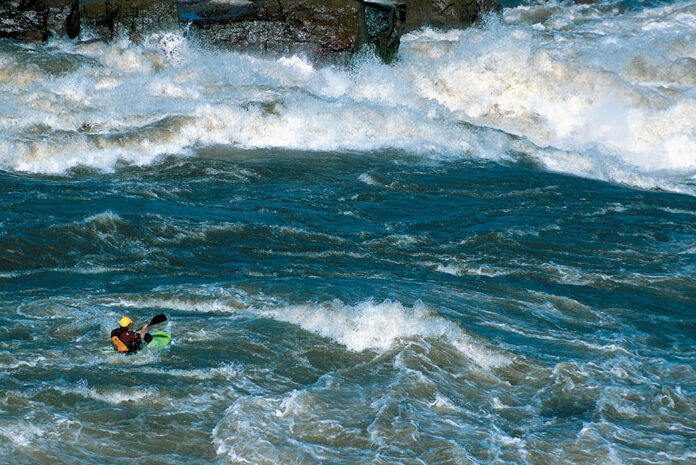 a whitewater kayaker paddling among large rapids on the Slave River