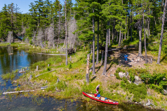 people at a lakeside campsite with a red canoe