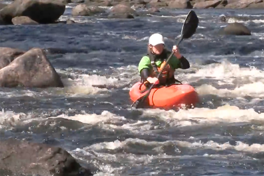 woman whitewater kayaker demonstrates the sweep stroke in a series of small rapids