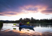 Woman paddling a kayak on a lake at sunset