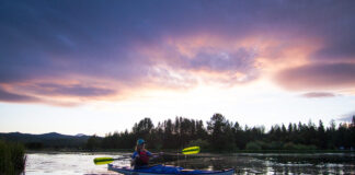 Woman paddling a kayak on a lake at sunset