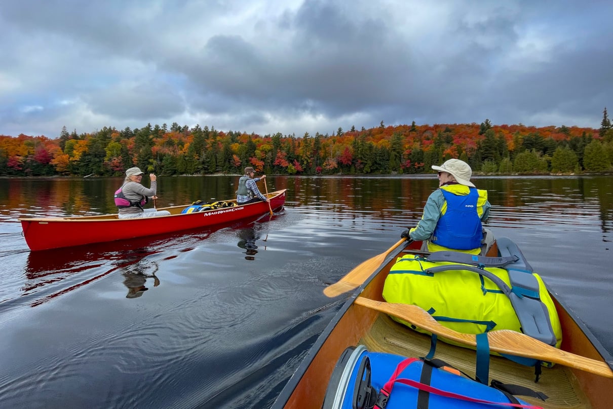 Group canoeing on a lake during fall.