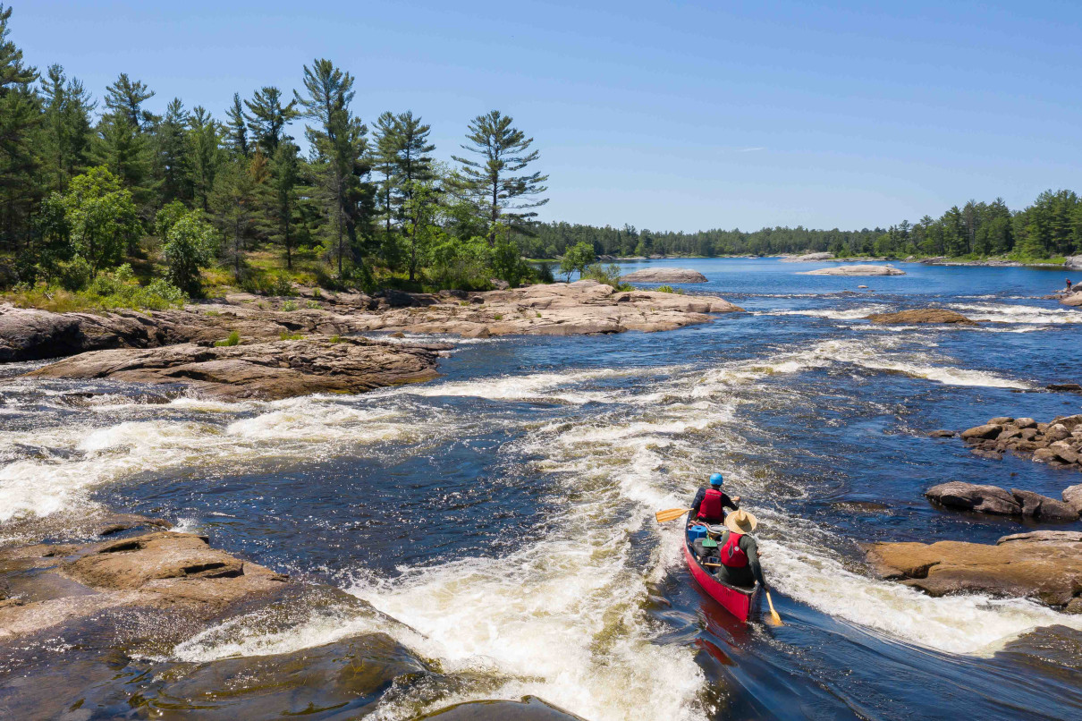 A tandem canoe entering a rapid.