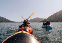people packraft on expansive waters surrounded by hills
