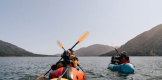 people packraft on expansive waters surrounded by hills