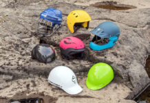 a selection of whitewater helmets are arranged on a river rock