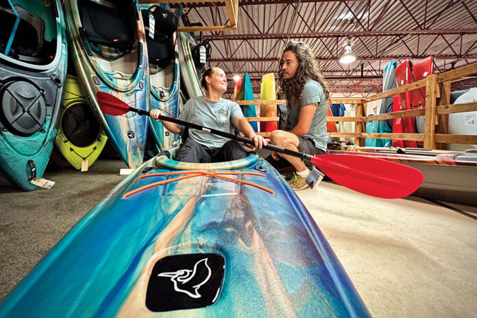 a salesman assists a woman purchasing a kayak