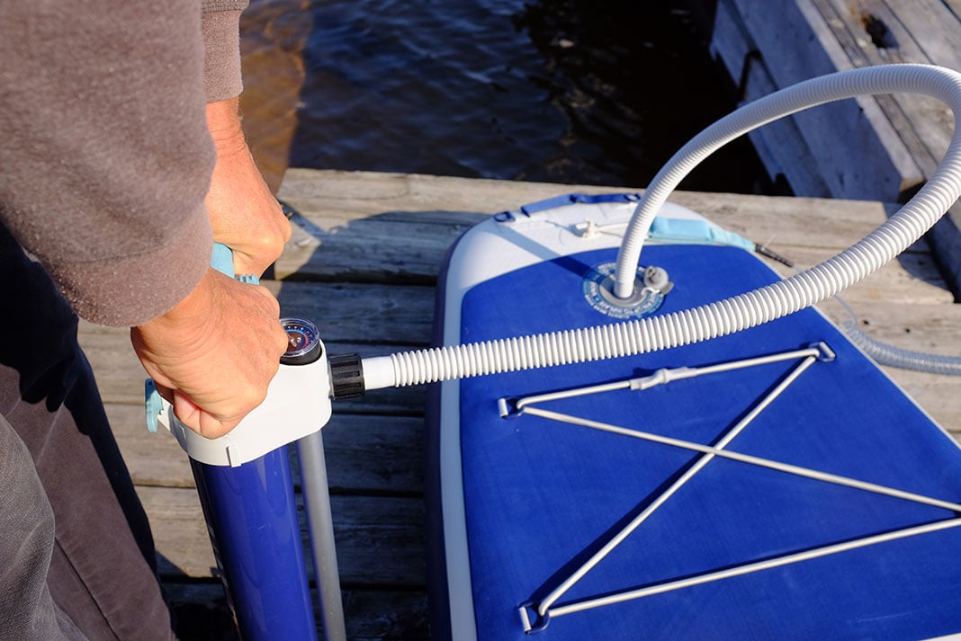 Person pumps up the ISLE Pioneer 2.0 paddleboard