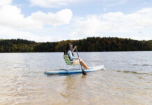 a woman demonstrates sit down paddleboarding using a lawn chair