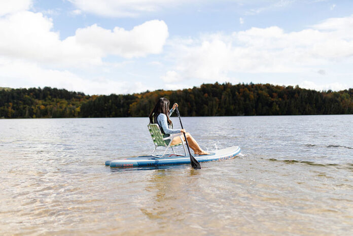 a woman demonstrates sit down paddleboarding using a lawn chair