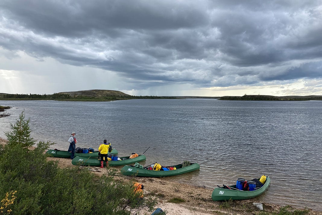 Stuart and Louise minding the canoes as the rest of the group finds a spot to wait out the coming rain