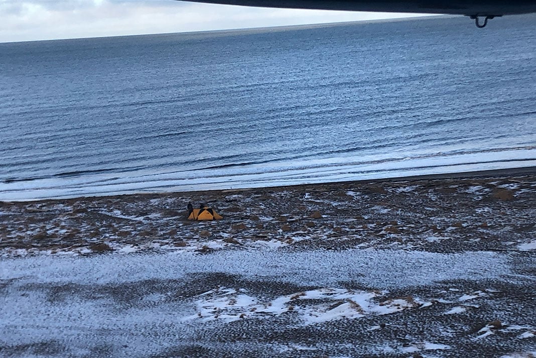 view out of a small airplane window at a tent on the Arctic tundra