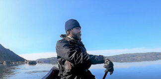 man paddles a canoe on a solo expedition in cold weather