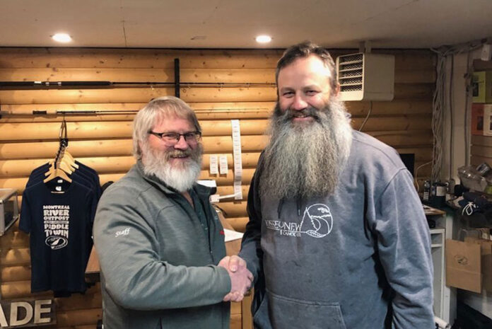 the previous and new owners of Churchill River Canoe Outfitters shake hands