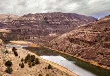 canoeist with permit travels down the John Day River surrounded by massive striated rock cliffs