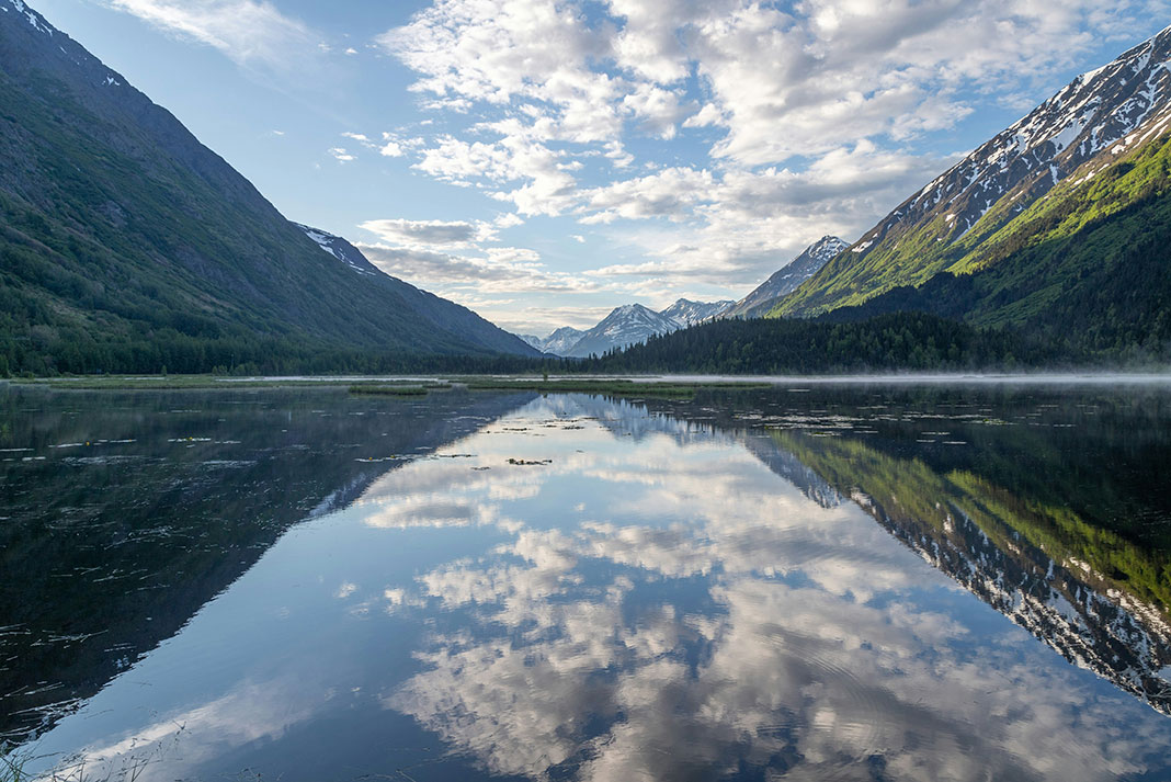 clouds reflected in water with hills rising from either side in Alaska