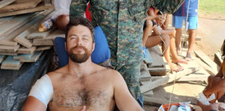 wounded man gives thumbs up while being attended by army medic after a gunfight during his Amazon River expedition