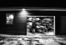 black and white photo looking into a garage full of paddling gear at night with garage door open