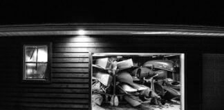 black and white photo looking into a garage full of paddling gear at night with garage door open