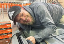 man leans over a fishing kayak while doing custom outfitting at a kayak fishing retailer