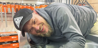 man leans over a fishing kayak while doing custom outfitting at a kayak fishing retailer