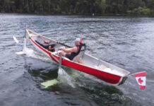 man travels on a lake in a hydrofoil canoe with a Canadian flag on the back