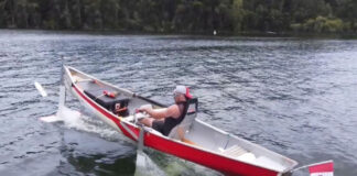 man travels on a lake in a hydrofoil canoe with a Canadian flag on the back