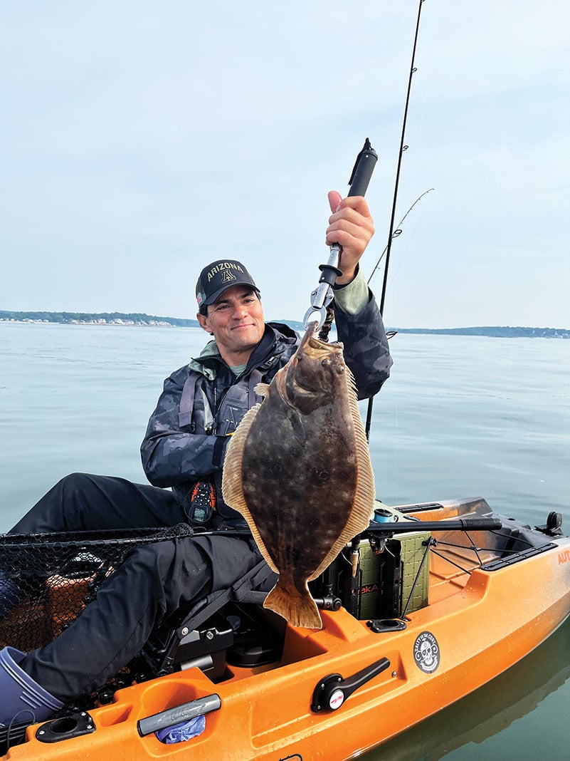 Kayak angler proudly holds up flounder in a lip gripper