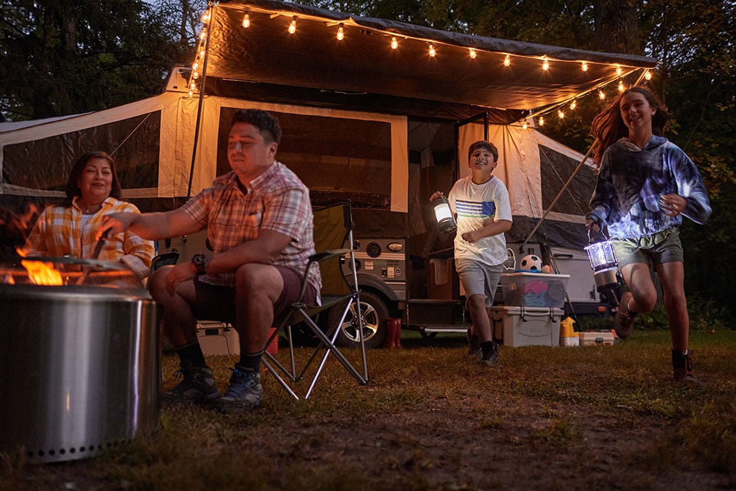 boy and girl exit a camping trailer with lanterns while on a kayaking vacation in Minnesota