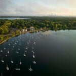 Your Guide To The 9 Most Magnificent Kayaking Destinations In Minnesota drone shot of Lake Harriet in Minnesota's Chain of Lakes showing moored sailboats with city in background