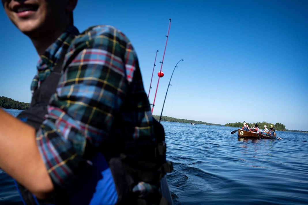 canoe trippers paddle across a lake in two boats equipped for fishing