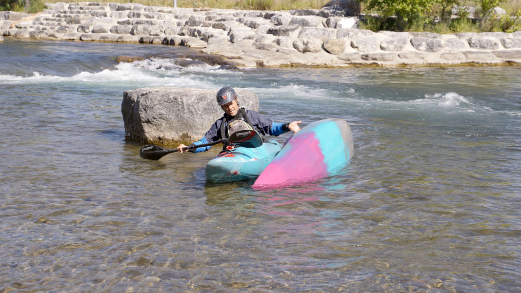 man demonstrates how to perform a kayak rescue in whitewater