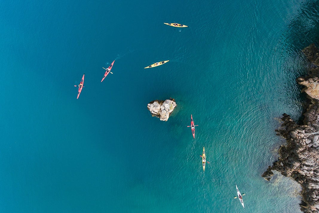 overhead view of a group of kayakers paddling in the turquoise waters of Greece