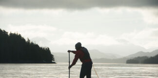 man silhouetted as he paddleboards across the dangerous Hecate Strait in British Columbia