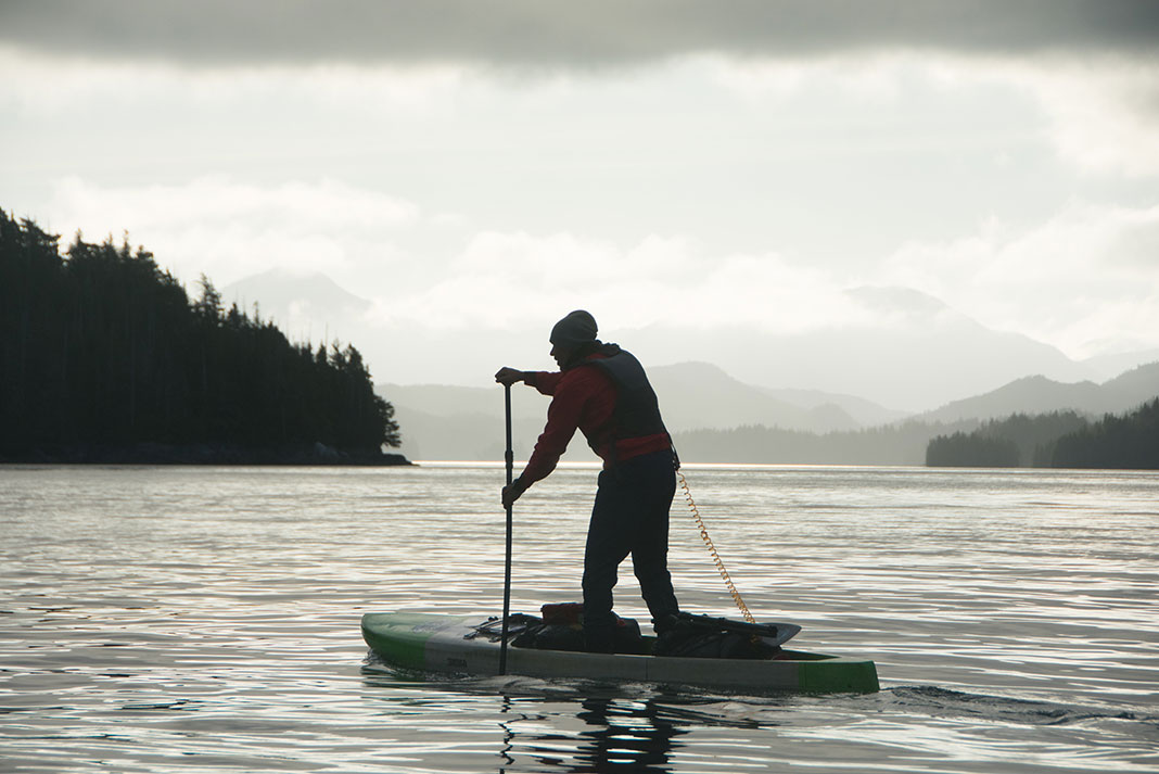 man silhouetted as he paddleboards across the dangerous Hecate Strait in British Columbia