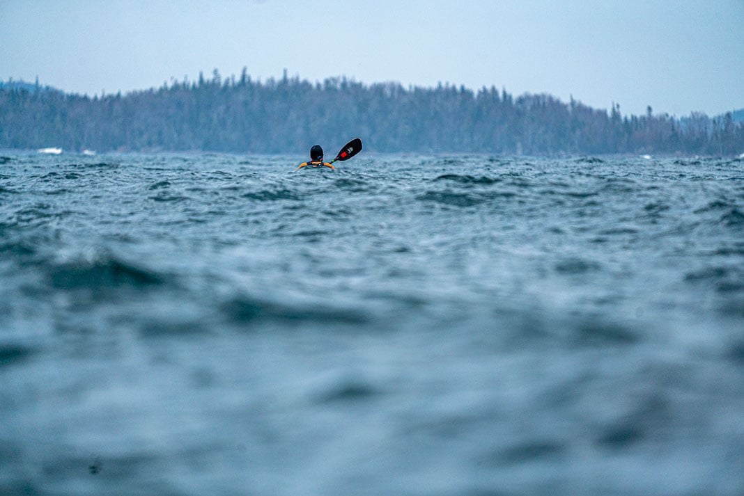 kayaker paddles through heavy seas on a rainy day