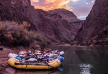 three whitewater rafts sit on the banks of a western river that requires a lottery system permit to paddle