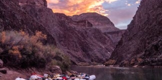 three whitewater rafts sit on the banks of a western river that requires a lottery system permit to paddle