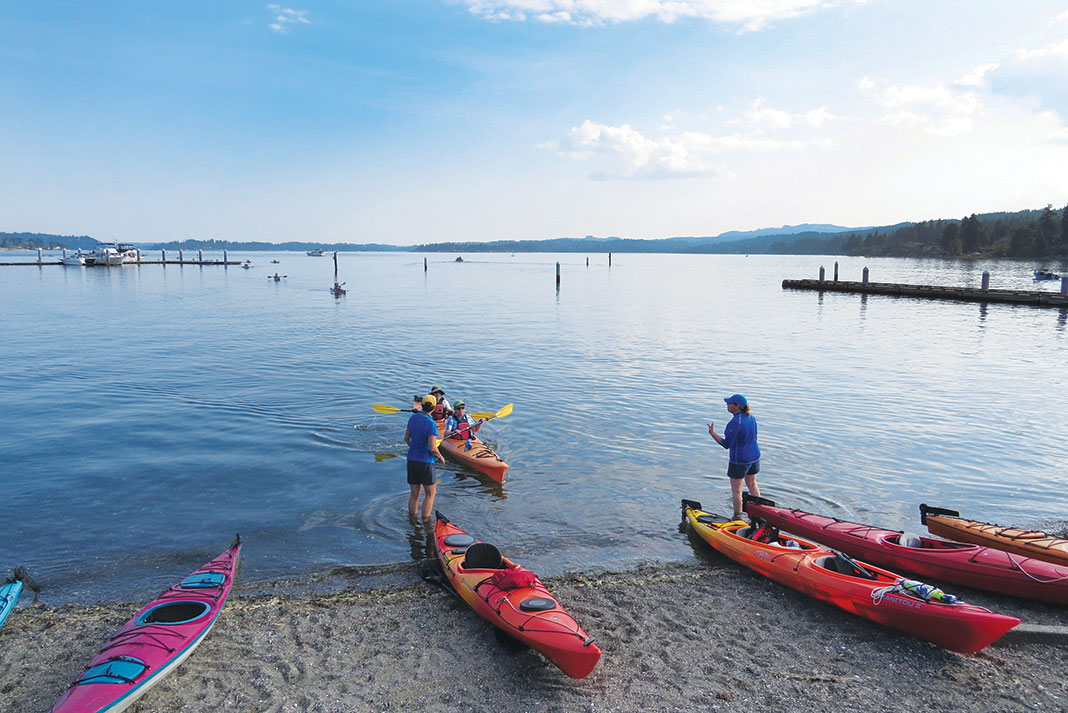 Kayaks beached on shore while people chat