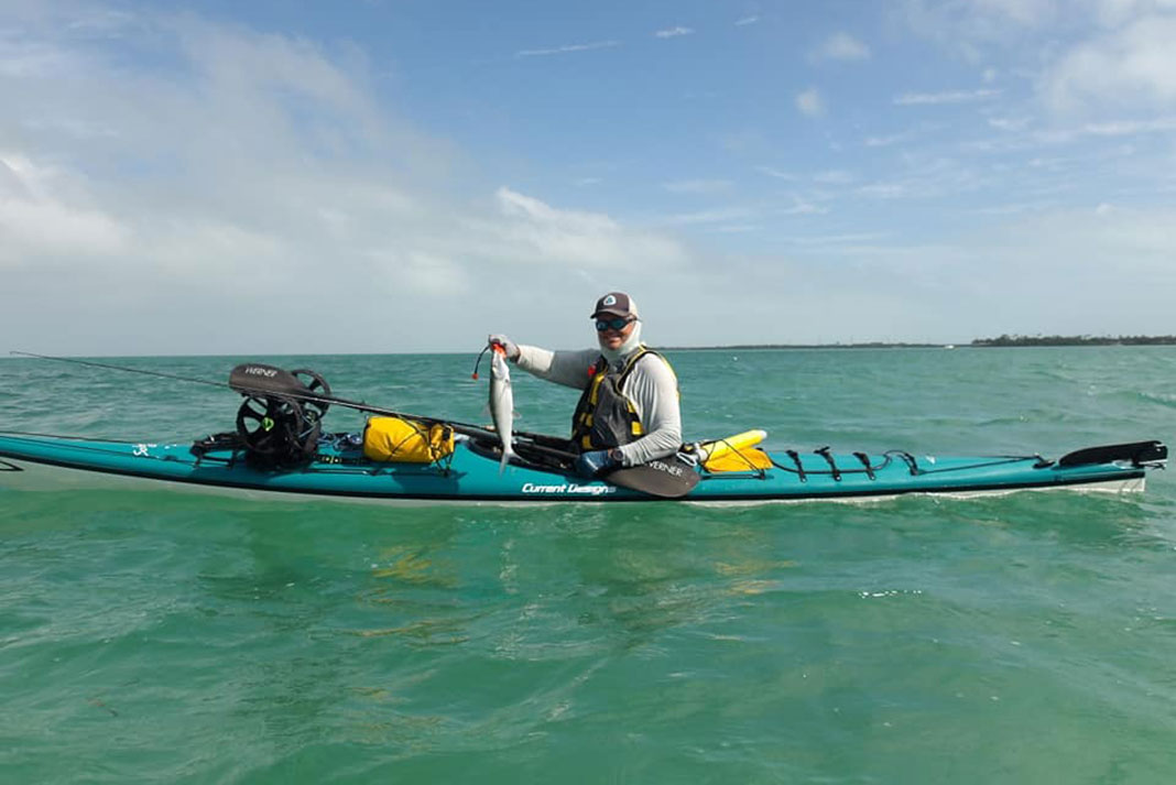 kayaker holds up a fish he caught