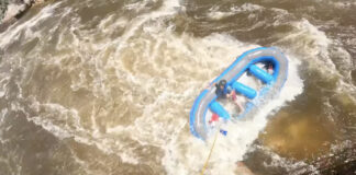 Kayaker pointing to rafter in need of rescue from hydraulic.