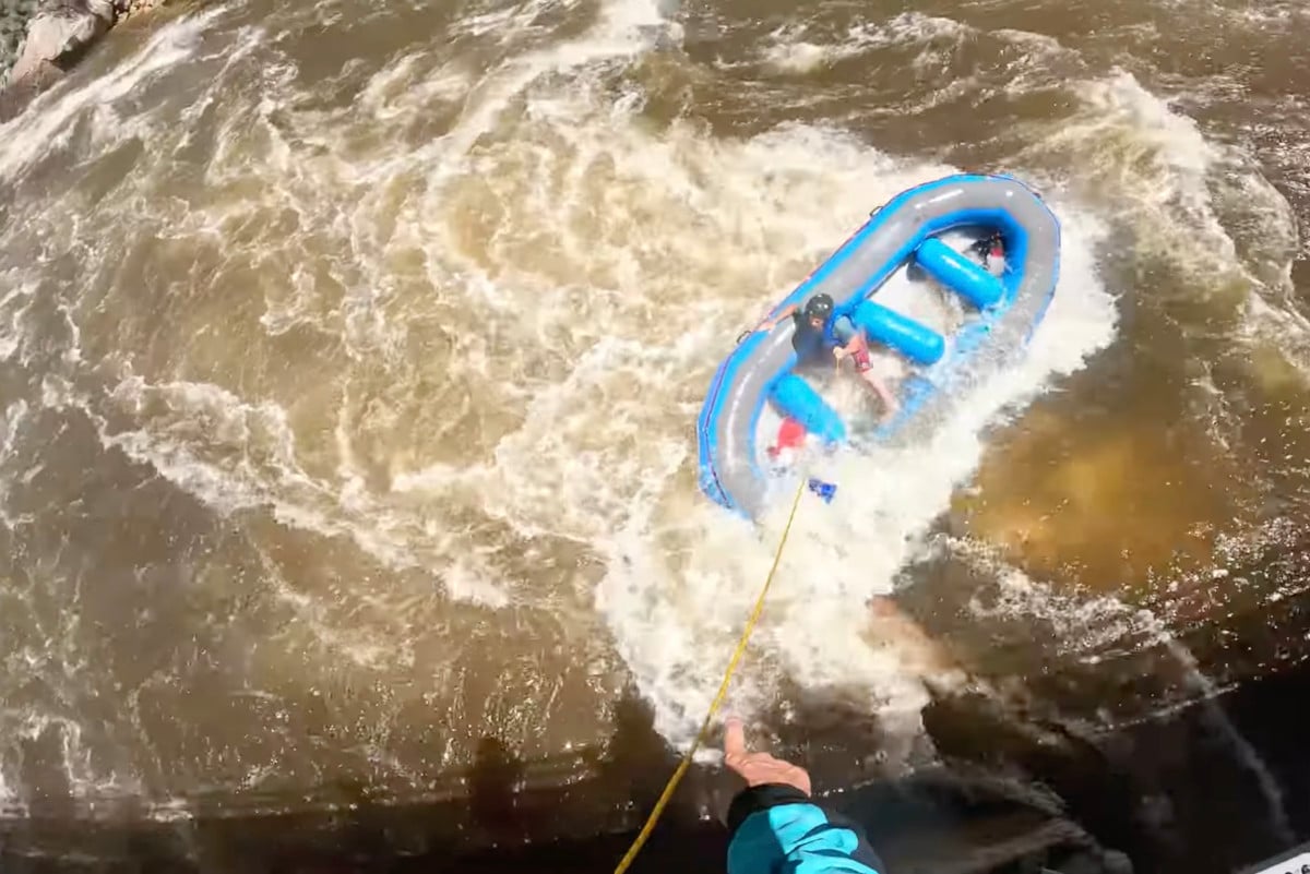 Kayaker pointing to rafter in need of rescue from hydraulic.