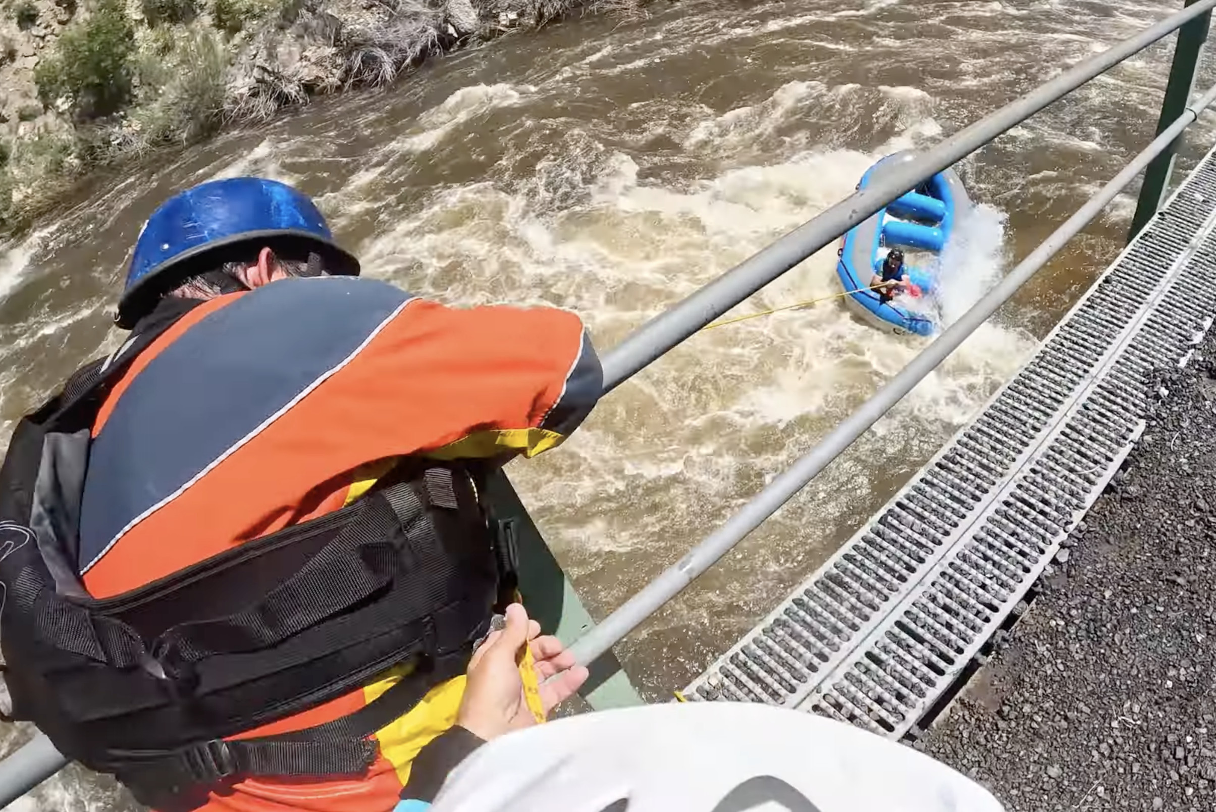 Kayaker pulls on rope to work raft out of hydraulic.