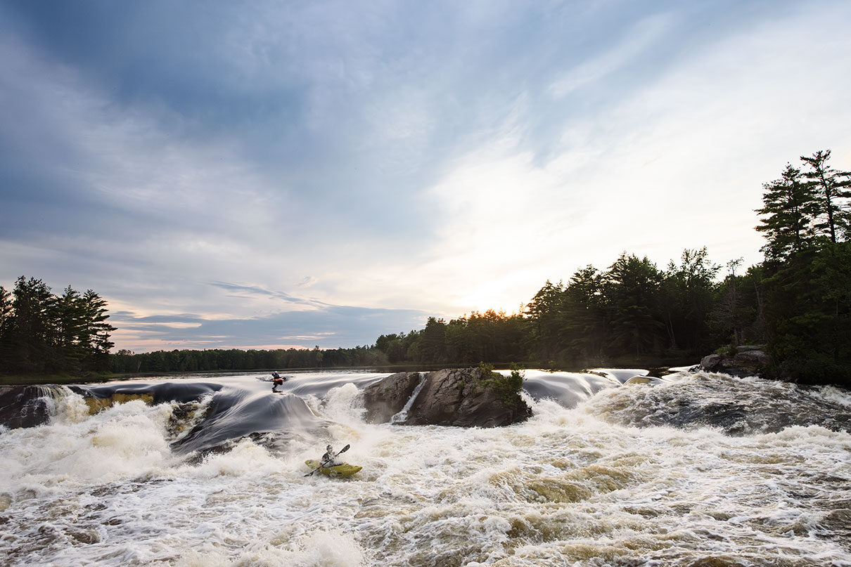 whitewater kayakers paddle through rapids on the Ottawa River in present day