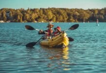 an adult and a child paddle an inflatable kayak together