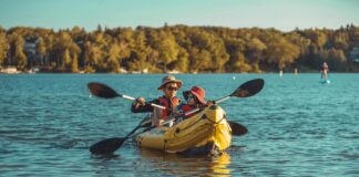 an adult and a child paddle an inflatable kayak together