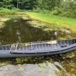 Canoe Review: The Radisson By BW Marine Products radisson canoe sits crosswise on narrow waterway with motor on stern