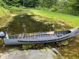 radisson canoe sits crosswise on narrow waterway with motor on stern