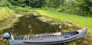 radisson canoe sits crosswise on narrow waterway with motor on stern