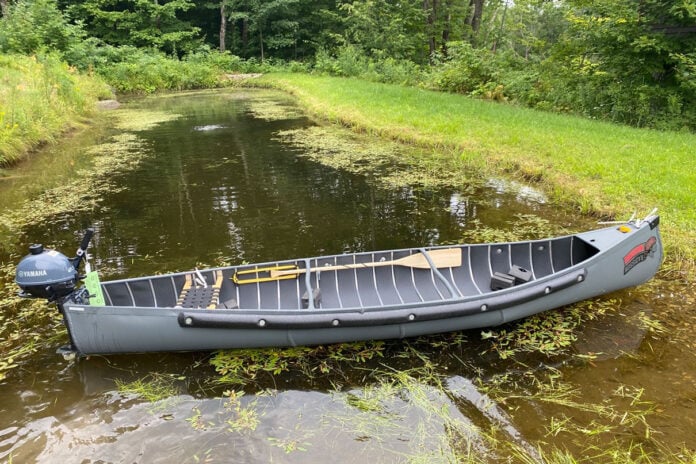 radisson canoe sits crosswise on narrow waterway with motor on stern